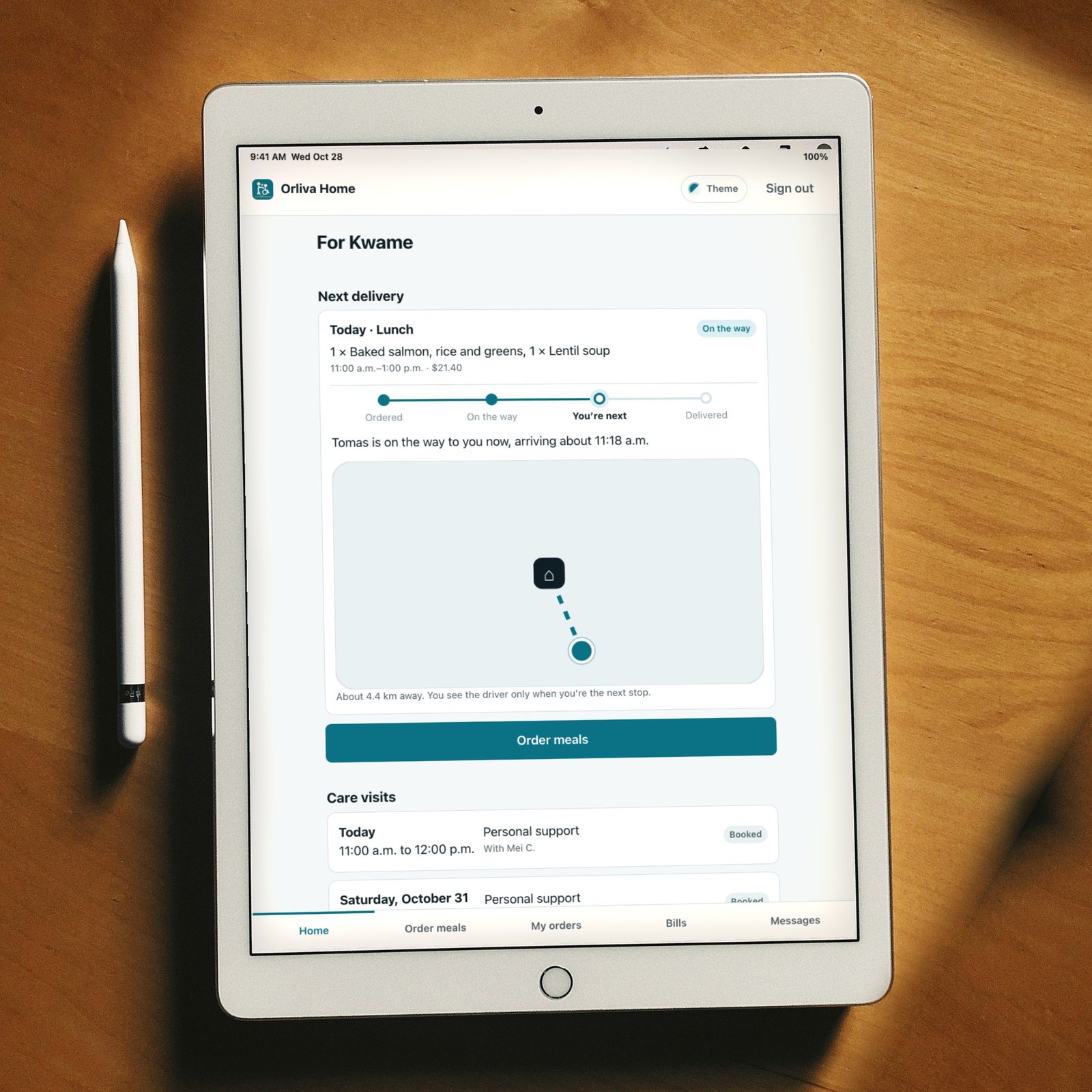 A tablet on a wooden table showing Orliva Home: today’s meal delivery and the week’s care visits, in large, clear type.